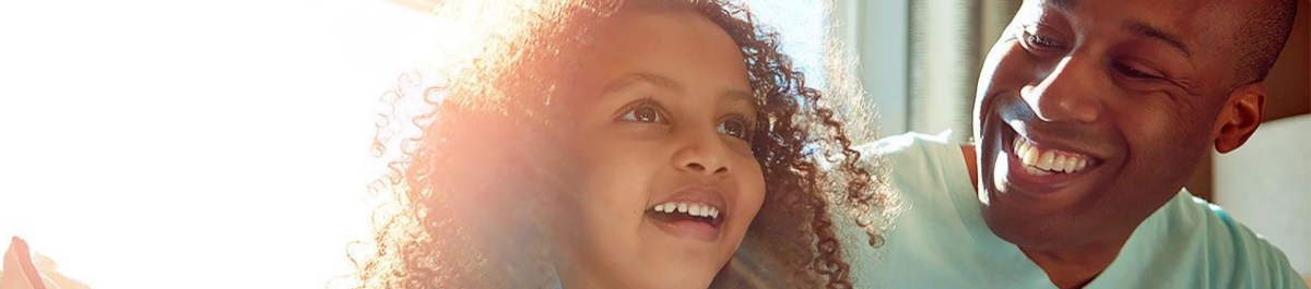 Father and school‑age daughter sharing joyful moment by window light, illustrating benefits of flexible spending account(s).