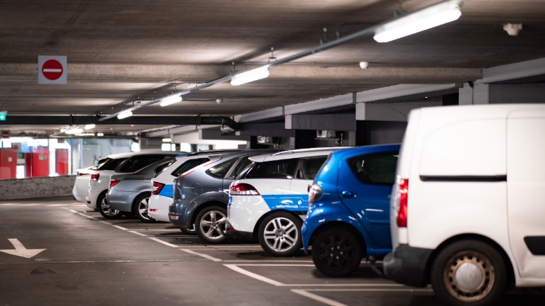 Row of parked cars in an underground parking garage, illustrating commuter benefits parking accounts for convenient and tax-advantaged employee parking solutions.