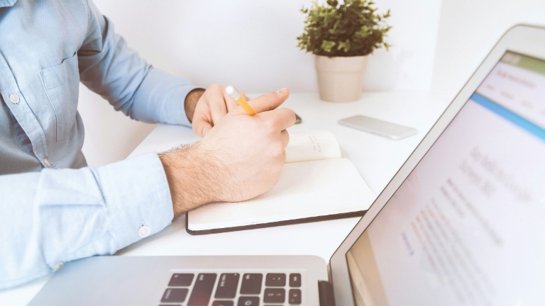 Person at desk with open laptop and notebook, exploring FSA Plan Compatibility, including HSA and Limited HRA considerations.