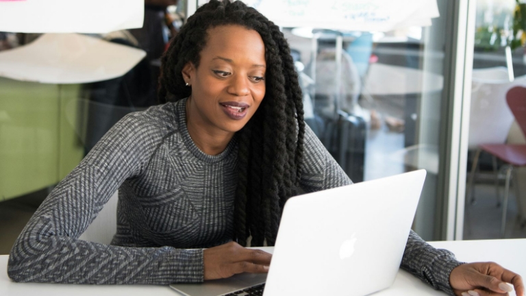 Glasses held in front of an eye chart by a smiling woman, symbolizing eye care affordability through FSA Options.