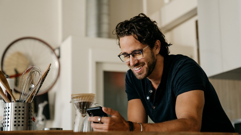 Relaxed man checking his phone at home, illustrating convenient mobile access to HRA benefits and account information.