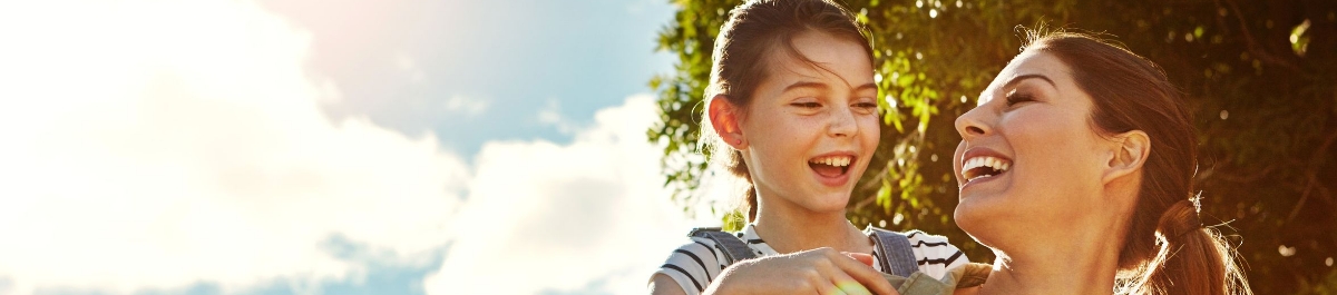 Happy woman and child laughing outside in sunlight, symbolizing health and savings through HSA benefits.