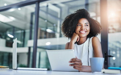 Employee smiling at a laptop in an office setting while considering HSA savings and financial wellness.