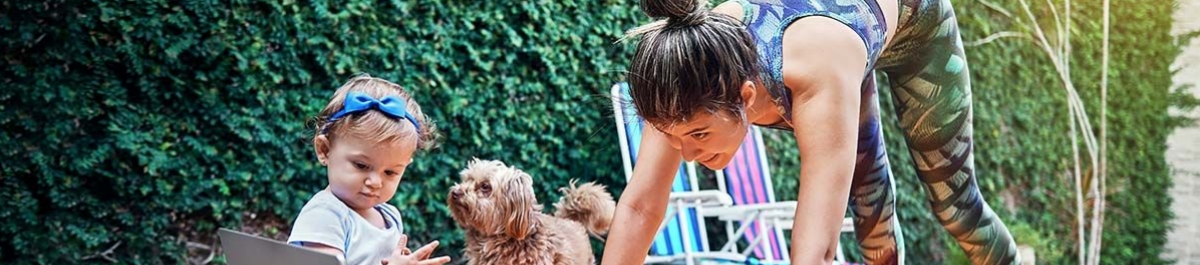 Woman exercising in a backyard while her toddler and dog play nearby, representing the flexibility of Lifestyle Spending Accounts to support family and fitness needs.