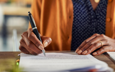 Person signing an open enrollment form with a pen