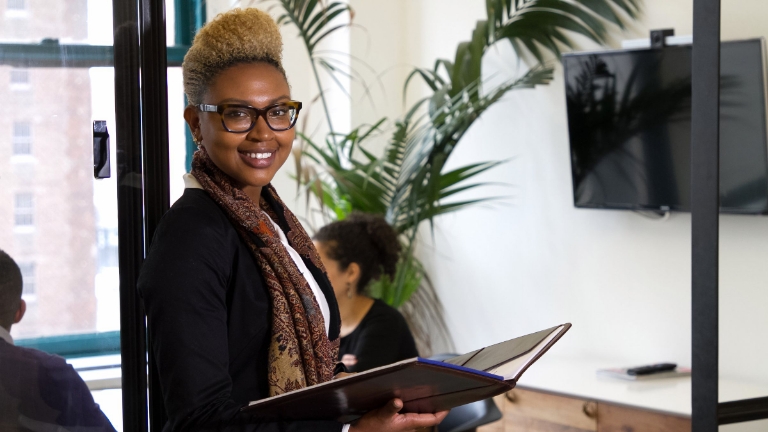 Businesswoman with open binder in professional setting, symbolizing efficiency and trust in Reoccurring Premium Collection.