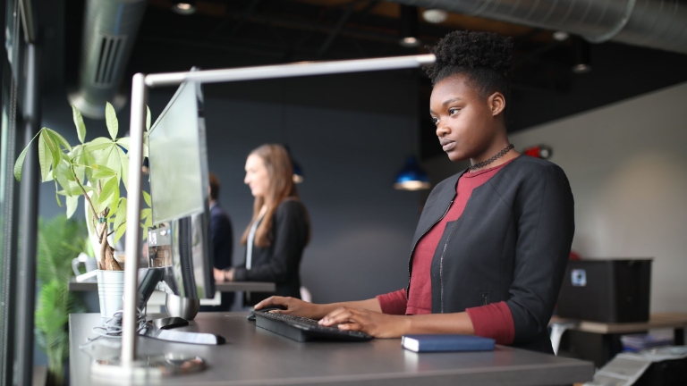 Professional woman at computer in bright office, showcasing modern Billing Services Technology Features for employee benefits.