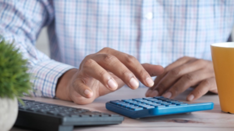 Business professional using calculator at desk, illustrating Premium Only Plans eligible premiums and pre-tax contribution management.