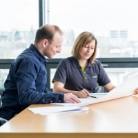 A man and a woman look over papers in a conference room